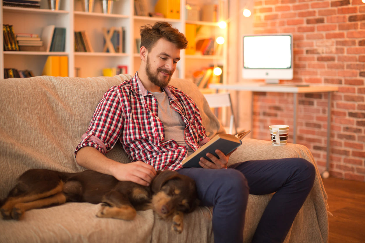 Eurolife blog - Man reading a book at home with his dog