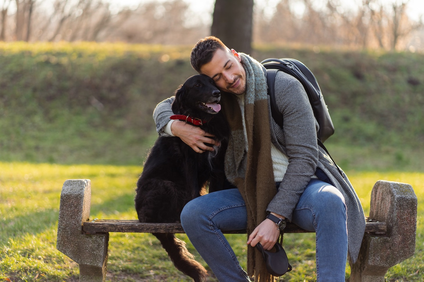 eurolife blog header - άνδρας με κασκόλ και παλτό καθισμένος σε παγκάκι στο πάρκο αγκαλιάζει τον μαύρο σκύλο του