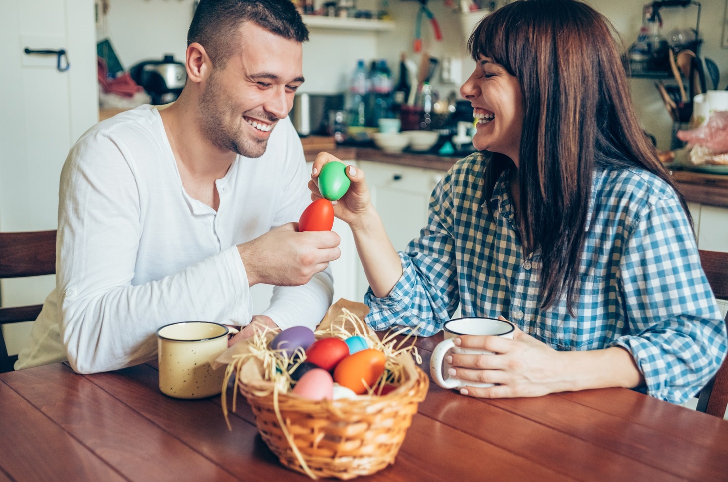 eurolife blog - νεαρό ζευγάρι κάθεται στο τραπέζι της κουζίνας και τσουγκρίζουν αυγά